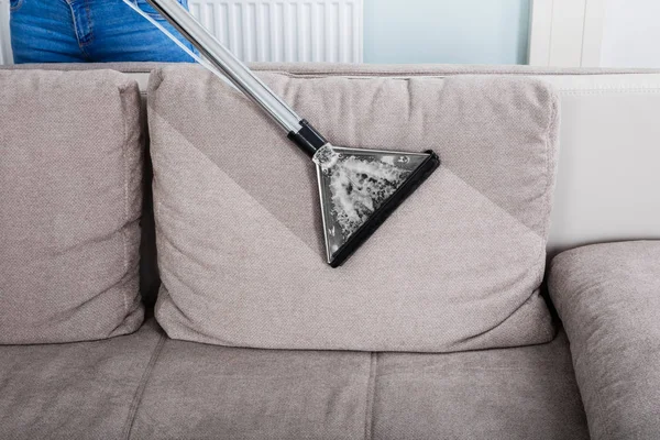 Frau putzt Sofa mit Staubsauger — Stockfoto