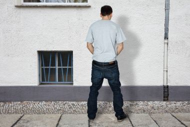 Man Peeing On Wall Of Building clipart