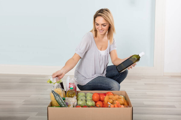 Женщина смотрит на коробку с продуктами
