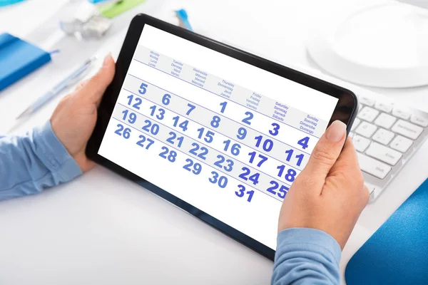 Mujer mirando calendario en la tableta digital —  Fotos de Stock