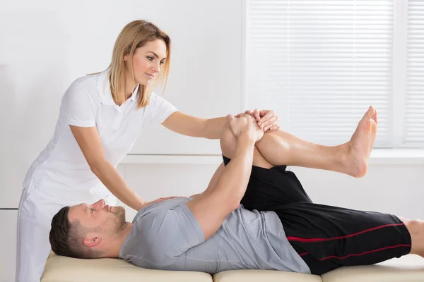 Physiotherapeut gibt Knieübungen — Stockfoto