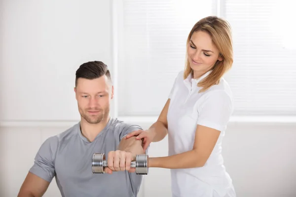 Fisioterapeuta ayudando al hombre a hacer ejercicio — Foto de Stock