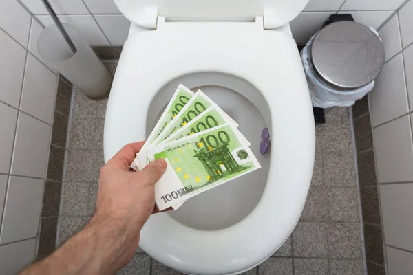 Homem jogando notas de euro no banheiro — Fotografia de Stock