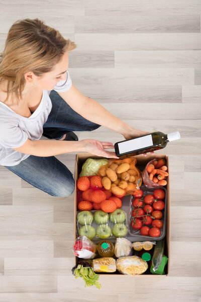 Женщина смотрит на коробку с продуктами
