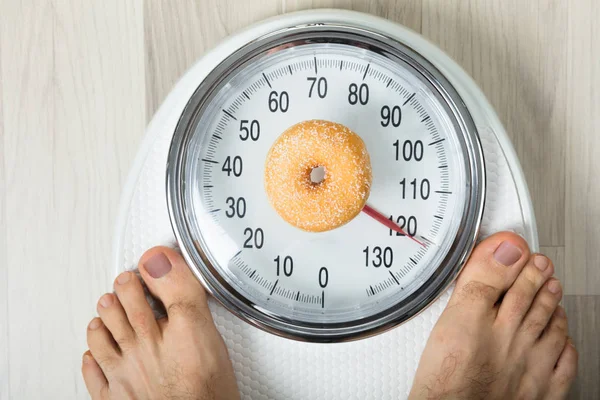 Donut und Person auf der Waage — Stockfoto