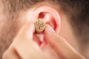 Doktor kulakta işitme cihazı koyarak