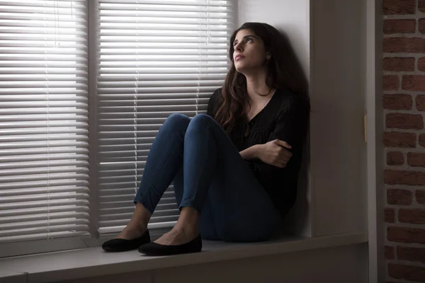 Frau sitzt auf Fensterbank — Stockfoto