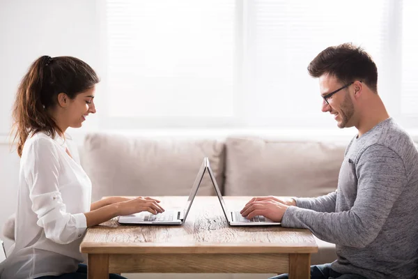 Casal sentado cara a cara usando laptops — Fotografia de Stock