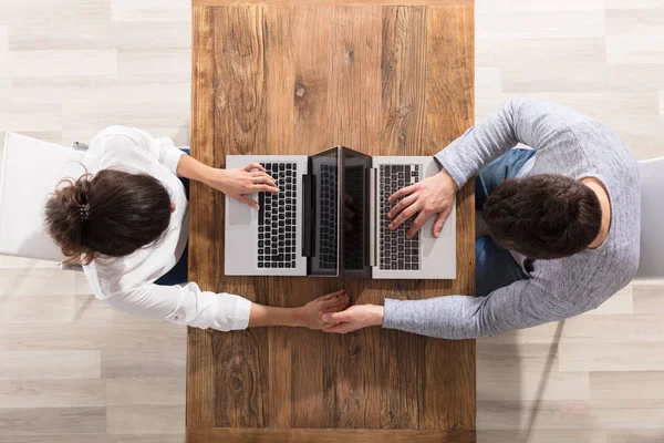 Paar sitzt sich mit Laptop gegenüber — Stockfoto