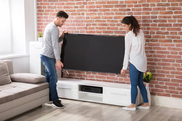 Para prowadzących nowy telewizor w domu — Zdjęcie stockowe