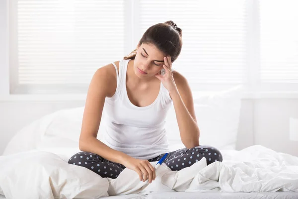 Mulher contemplada sentada na cama amassada — Fotografia de Stock