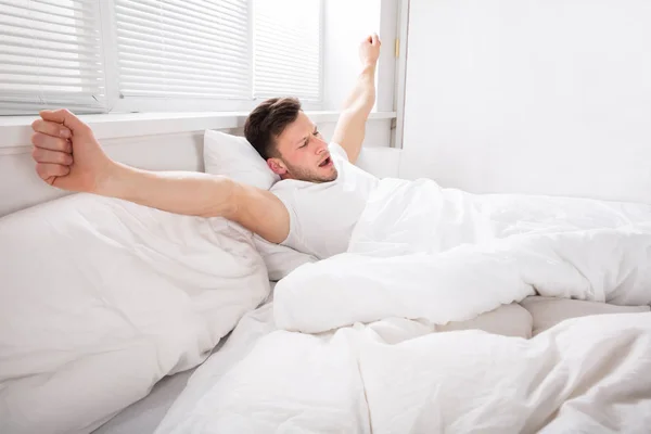 Homem esticando as mãos na cama — Fotografia de Stock