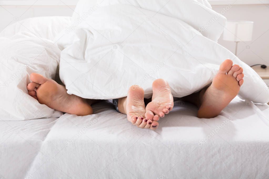 male and female legs under bed sheet