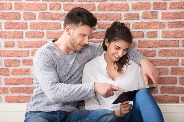 Paar sitzt zu Hause und schaut auf Tablet — Stockfoto