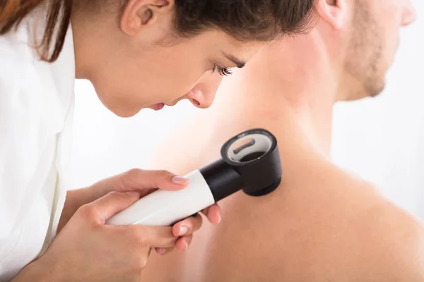 Dermatologist examining patient skin — Stock Photo, Image