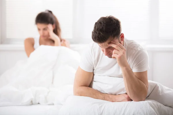 Worried couple sitting on bed — Stock Photo, Image