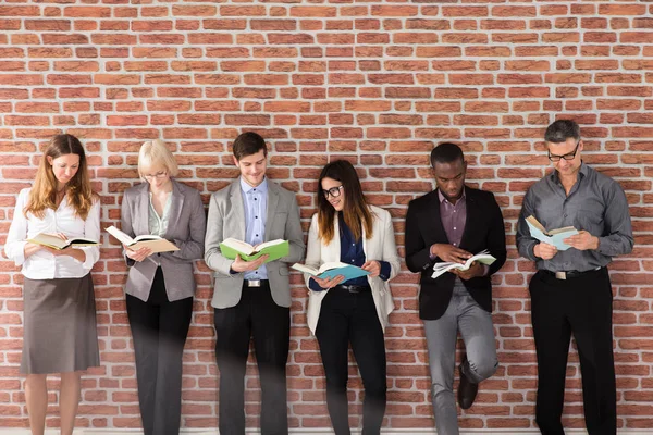 Diverse Group Businesspeople Standing Brick Wall Reading Books — Stock Photo, Image