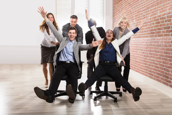Χαμογελώντας Επιχειρηματίες Παίζουν Μαζί Περιστρεφόμενη Καρέκλα Στο Γραφείο — Φωτογραφία Αρχείου