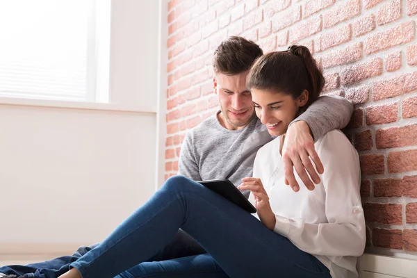 Pareja sentada en casa mirando la tableta —  Fotos de Stock