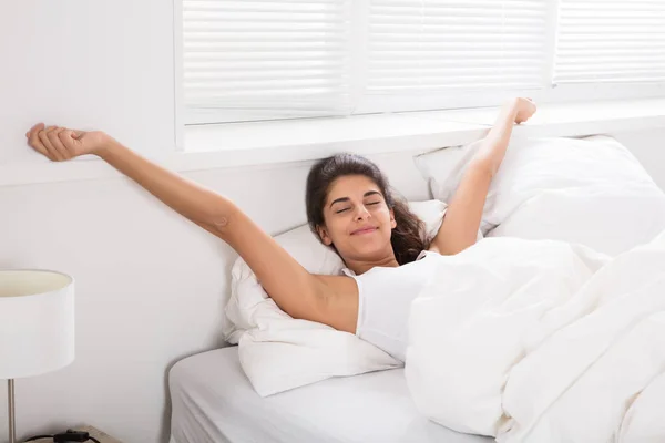 Žena natahovat ruce v posteli — Stock fotografie