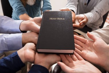 Holy Bible Over The Hands Of Diverse People clipart