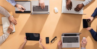Dizüstü bilgisayarlar ve Office dijital tablet ile masa üzerinde işadamları'nın el havai görünümü