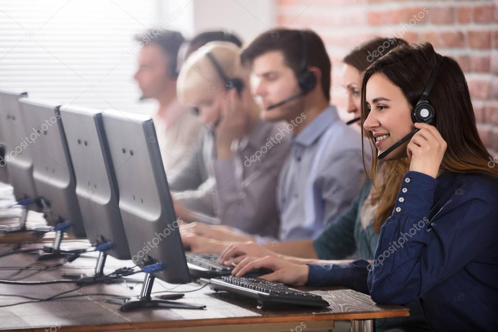 Positive Female Customer Services Agent With Headset Working In A Call Center