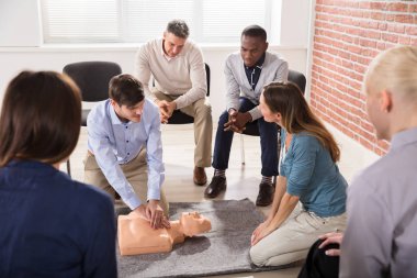 CPR eğitim öğrencisi için kukla üzerinde gösterilen genç erkek eğitmen