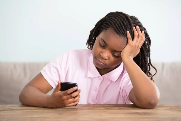 Verveeld meisje kijkend naar telefoon — Stockfoto