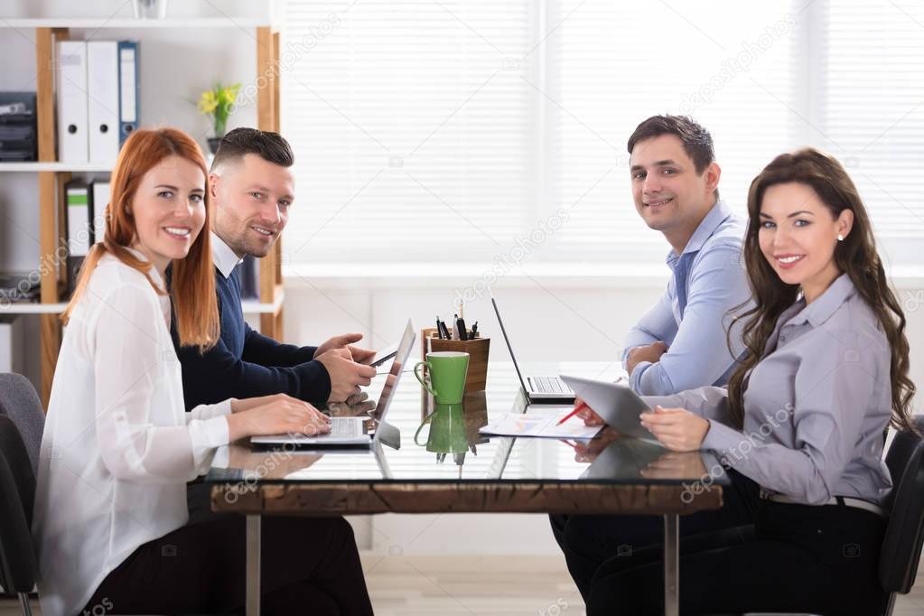 Happy Business People Using Electronic Devices At Workplace In Office