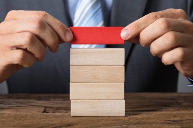 Ahşap kule üzerinde blok yerleştirme iş adamı