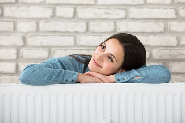 Mujer detrás del radiador de calefacción — Foto de Stock