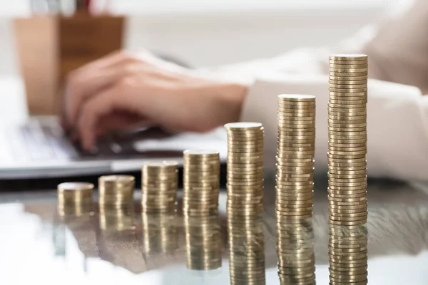 Pilas de monedas y manos femeninas en el ordenador portátil — Foto de Stock