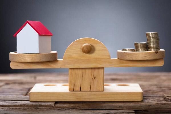 Model Home And Coins On Weighing Scale