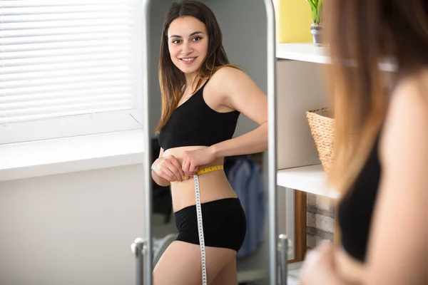 Kvinna mäta magen i spegeln — Stockfoto