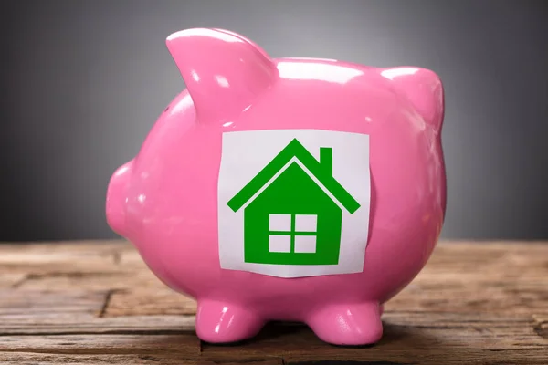 Zöld könyv ház rózsaszín piggybank — Stock Fotó
