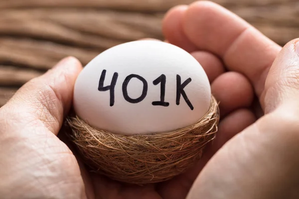 Händer som håller 401k ägg i boet — Stockfoto