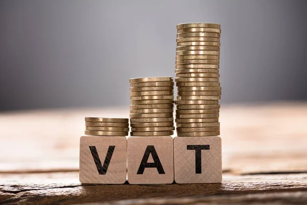 Vat text on blocks with stacks of coins — Stock Photo, Image