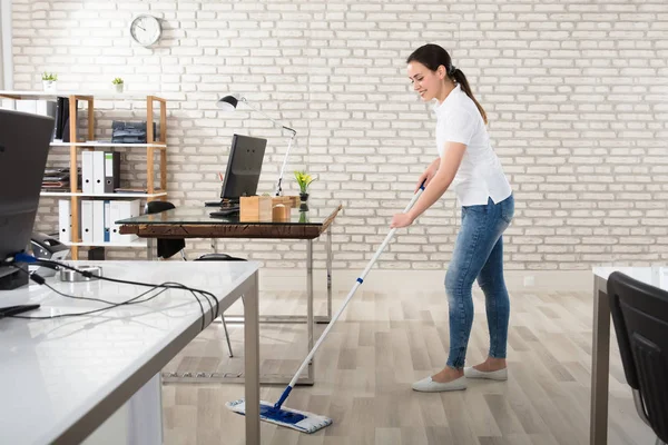 Mladá žena čištění podlahy — Stock fotografie
