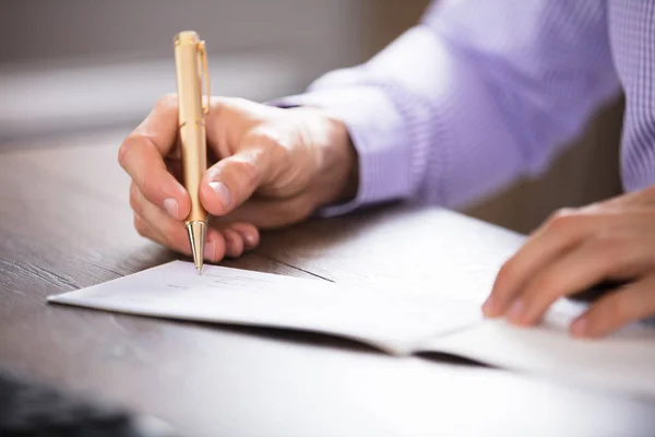 Die Hand des Geschäftsmannes unterschreibt den Scheck — Stockfoto