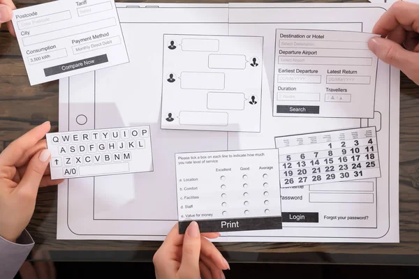 Designers Developing Mobile Application On Paper Over Desk