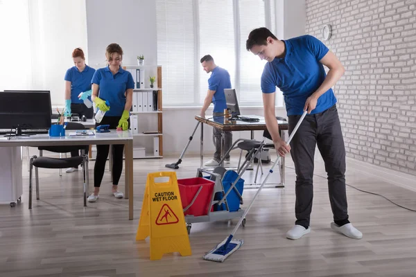 Grupo Conserjes Limpiando Oficina Moderna Con Precaución Signo Piso Húmedo —  Fotos de Stock