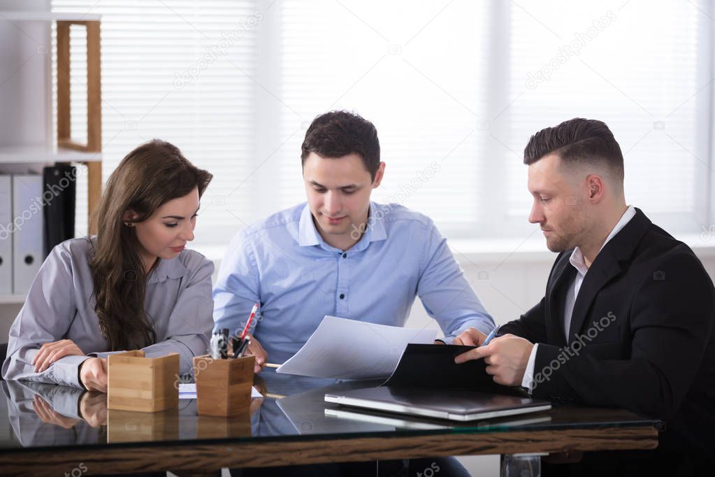 Couple Talking With Advisor During Meeting In Office