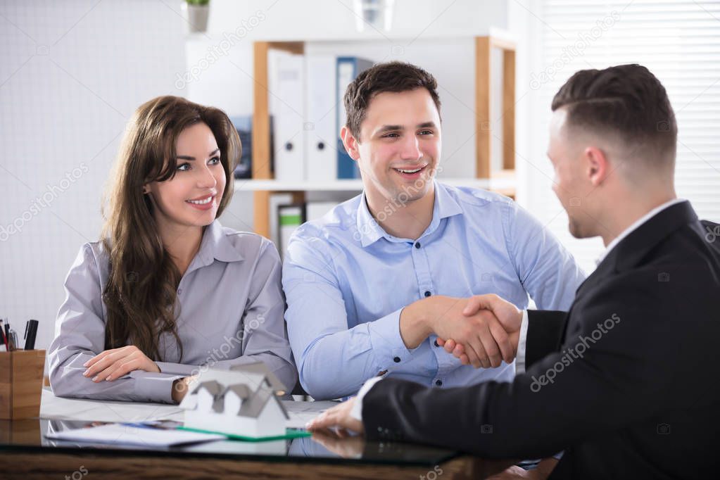 Young Couple Shaking Hands With Architect Or Mortgage Broker