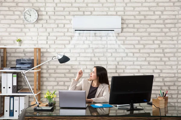 Empresária operando ar condicionado — Fotografia de Stock