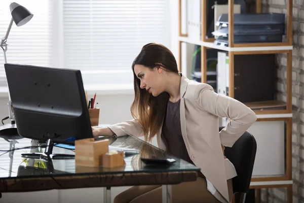 Empresaria teniendo dolor de espalda en el lugar de trabajo — Foto de Stock