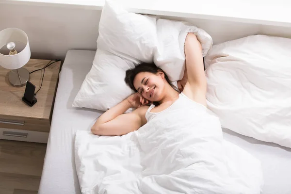 Vrouw die zich uitstrekt op bed — Stockfoto