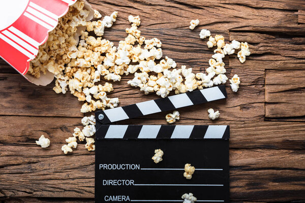 Clapperboard And Popcorn On Wood 