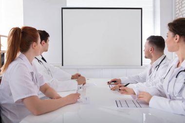 Erkek ve kadın doktorlar toplantıda beyaz tahta bakarak
