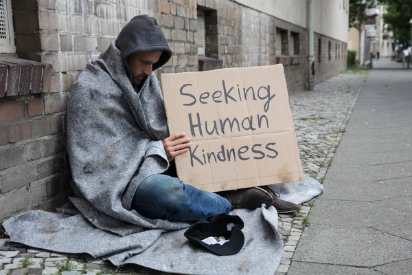 Бездомний чоловік сидить на вулиці — стокове фото